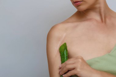 Kadında yara izi, kırık kol. Aloe vera yaprağı, çıplak omuzları ve temiz cildi olan seksi bir kadın portresi. Boşluğu kopyala