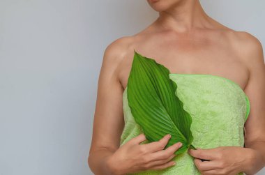 Yeşil yaprak, yara izini gösteriyor. Gri arka planda yara izi olan havluyla seksi bir kadın cesedi. Yara Tedavisi.