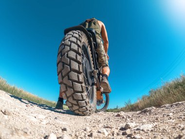 Düşük açılı, motorlu, yakınlaştırılmış elektrikli motosiklet tekerleğinin yaratıcı fotoğrafı. Dikiz aynası. Mavi gökyüzü ile kavisli ufuk.