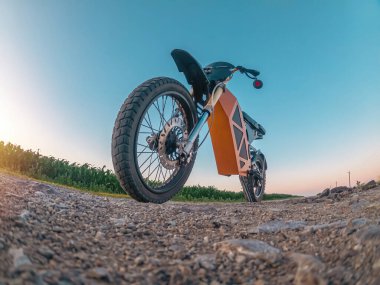 Düşük açılı, zum yapmış elektrikli motosikletin yaratıcı bir fotoğrafı. Mavi gökyüzü ile kavisli ufuk.