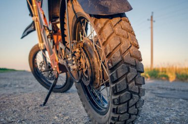 Elektrikli motosiklet tekerleği yolda, güneş ışığı altında. Yakın plan. Modern kişisel ulaşım. Gün batımı.