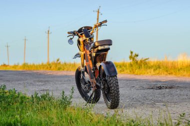 Elektrikli motosiklet, scooter, elektrikli bisiklet. Modern çevre dostu ulaşım. Dikiz aynası. Kırsal yol arkaplanı.