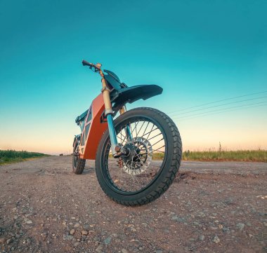 Scooter, elektrikli motosiklet. Modern çevre dostu ulaşım. Ön manzara. Gün batımında kırsal yolun arka planı.