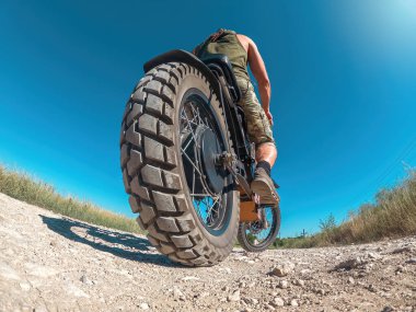 Scooter, motorcuyla elektrikli motosiklet. Çevre dostu ulaşım. Alt manzara. Gün batımında ufkun eğimli yayı.