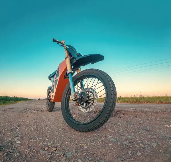 Scooter, elektrikli motosiklet. Modern çevre dostu ulaşım. Ön manzara. Gün batımında kırsal yolun arka planı.