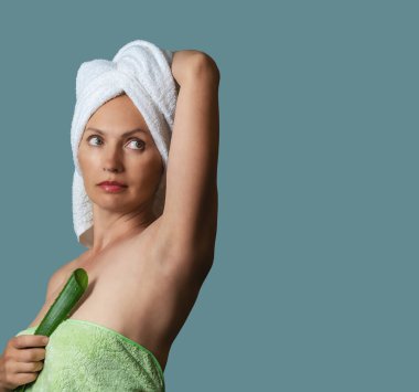 Mavi arka planda elinde aloe vera yaprağı tutan hayalperest kadın. Ellerini başının arkasına koy. Yenilenme etkisi. Boşluğu kopyala.