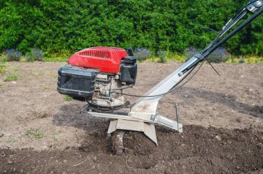 Elle benzin ekicisi toprağı sürer. Motor ekicinin pervanelerine yakın çekim. Toprak ekicinin altından uçup gidiyor. Çiftçilik kavramı.