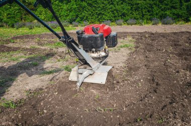 Elle benzin ekicisi toprağı sürer. Motor ekicinin pervanelerine yakın çekim. Toprak ekicinin altından uçup gidiyor. Çiftçilik kavramı.