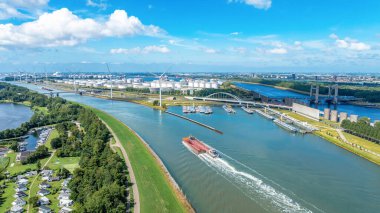 Su kanalı, gemi, yel değirmeni, Hollanda. Açık güneşli bir günde şehir kanalının gemi, rüzgar türbinleri, sanayi binaları, köprüleri görüntüsü.