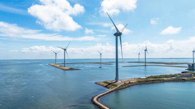 Okyanustaki rüzgâr çiftliği, Hollanda. Bulutlu gökyüzünün altındaki su üzerindeki yel değirmenlerinin havadan görünüşü. Sürdürülebilir kalkınma, yenilenebilir enerji, elektrik üretimindeki yeni teknolojiler.