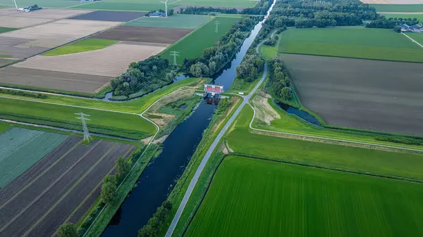 Köprü ile su kanalı. Hollanda 'daki su kanalının yanında tarım arazileri, tarlalar, elektrik direkleriyle çevrili ormanlar. Kırsal alan.