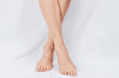 Beyaz havluyla bacak bacak bacak üstüne atmış. Çıplak kadın bacakları ayak parmaklarının üzerinde duruyor. Yıkandıktan sonra temiz ve yumuşak cilde dikkat et. Güzellik merkezi konsepti.