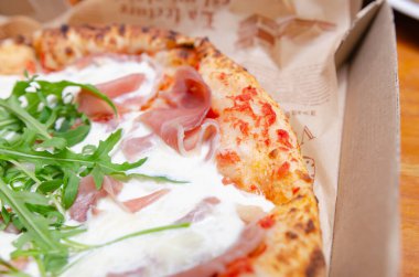 Mutfakta ekmek yapan bir fırıncı Parma jambonlu pizzayla karton kutuda İtalyan usulü