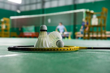 Badminton raketleri ve beyaz kremalı badminton mekikleri oynadıktan sonra ya da yeşil zeminde dünya çapında badminton severler için kapalı badminton kortunun yumuşak odaklanma konseptinde oynadıktan sonra..