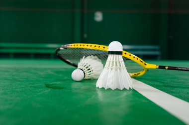 Badminton raketleri ve beyaz kremalı badminton mekikleri oynadıktan sonra ya da yeşil zeminde dünya çapında badminton severler için kapalı badminton kortunun yumuşak odaklanma konseptinde oynadıktan sonra..