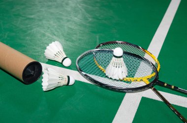 Badminton raketleri ve beyaz kremalı badminton mekikleri oynadıktan sonra ya da yeşil zeminde dünya çapında badminton severler için kapalı badminton kortunun yumuşak odaklanma konseptinde oynadıktan sonra..