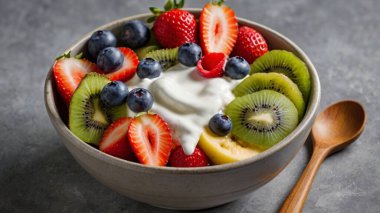 Bir kase taze meyve salatası, müsli ve Yunan yoğurdu gri arka planda mesaj için boş yer var.