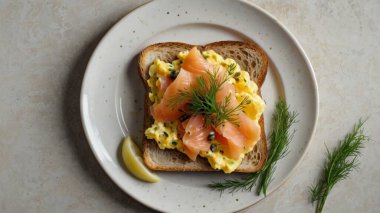 Taze dereotu ve kapari ile süslenmiş çırpılmış yumurta ve tütsülenmiş somon balığıyla bir tost..