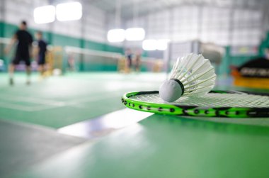 Badminton raketleri ve beyaz kremalı badminton mekikleri oynadıktan sonra ya da yeşil zeminde dünya çapında badminton severler için kapalı badminton kortunun yumuşak odaklanma konseptinde oynadıktan sonra..