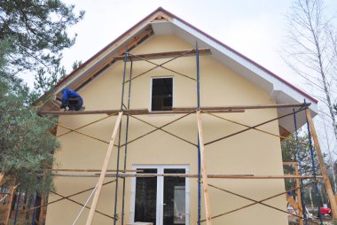 Building contractor installing fascia and soffit board on new painted house. 