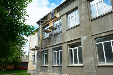 Building contractor applying stucco, plastering, and finishing the facade for painting.House wall renovation with plaster and painting outdoors.