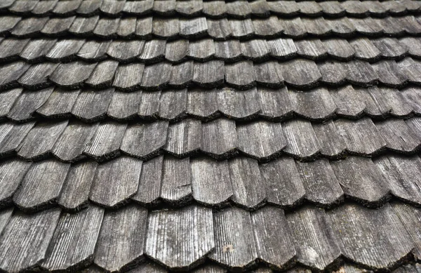 Gray, wooden roof tiles background, texture. A close-up of an old gray roof covered with wooden tiles.