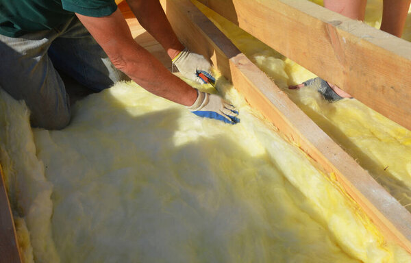 Roofer contractor laying insulation in problem area  during house roofing construction rooftop renovation. House roofing construction insulation concept. 