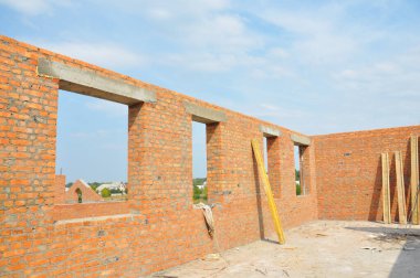 Pencereleri, beton kiremitleri ve çatısı olmayan tamamlanmamış tuğla ev inşaatı.
