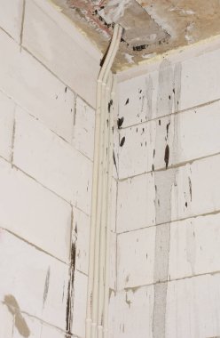 Yeni evin inşaat duvarında elektrik kabloları var. Havalandırılmış beton duvarda elektrik gizli kabloları kurulumu.