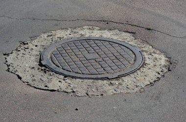 Asfalt yolundaki metal rögar kapağını beton onarımıyla kapatın.