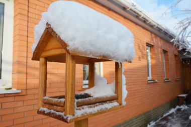 Tahta kuş yemliği, kuş besleme evi, ayçiçeği tohumlu sallanan kuş masası soğuk kışın örtülü karı.