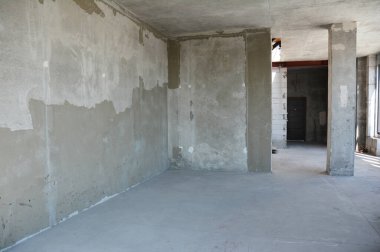Apartment renovation of a newly built house with concrete floor, finishing on walls, and a concrete column, or pillar. 