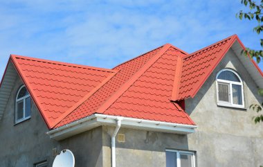 House metal roof waterproof problem area with rain gutter corner pipeline and unfinished plastering house wall facade during renovation.