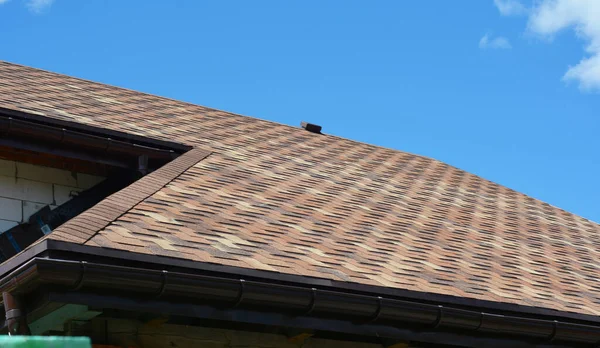 Close up on asphalt shingles roofing construction. House asphalt shingles roofing construction waterproofing with vent on rooftop.