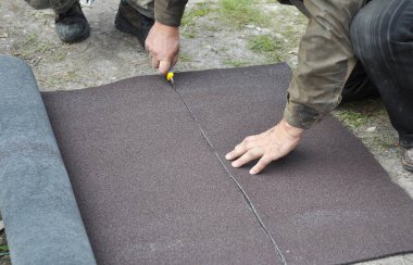 Çatı inşaatı ve onarım: inşaat müteahhitleri asfalt kiremitleri için asfalt doymuş çatı döşeme altyapısını kesiyor.