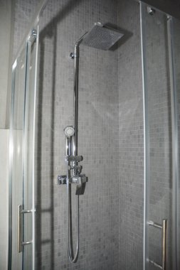 Lüks bir banyo duvarına yakın plan, kare paslanmaz çelik duş seti, gri modern bir banyoda üstten sprey..