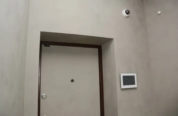 Modern house entrance door interior with  smart house system, security camera, smoke alarms and fire detection. A smart home allows homeowners to control appliances, thermostats, lights, and other