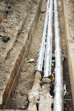 Yeraltı sıcak su borularının yalıtımlı olarak yerleştirilmesi, yerleşim yerinin yakınındaki siperlerde bölgesel ısınma boruları.