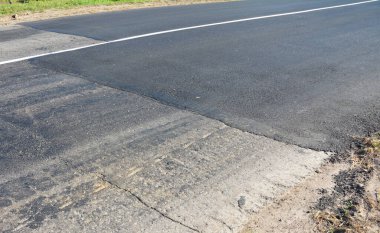 Yeni asfalt yolu döşeyip onarıyor.