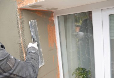 Dış duvarı yalıtmak ve sıvamak, pencerenin etrafına köpük kaplamak bir inşaat müteahhidi fiberglas üzerine alçı sürüp pencerenin çevresini sağlamlaştırıyor..