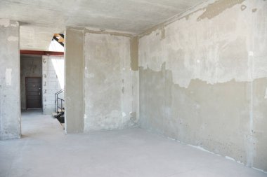 Duvarları sıva kaplı, inşaat halindeki ev odası.