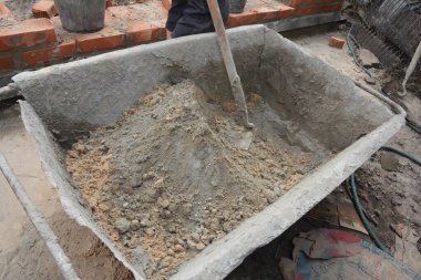 İnşaat işçileri kum ve çimentoyu karıştırmak için beton hazırlıyor.