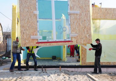 KYIV, UKRAINE - 23 Haziran 2024: Çerçeve inşaatı sırasında Yapısal İzolasyon Panelleri (SIPS) kuranlar. 