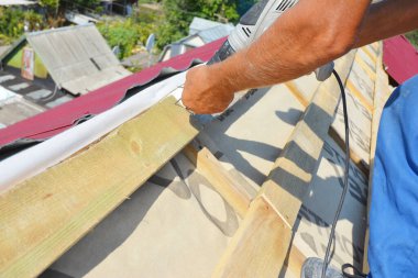 Metal çatı inşaatı sırasında çatı çatısı: Buhar, nem bariyeri ve çatı kaplaması üzerine döşenmiş hafif metal çatı örtüsü ile tamamlanmamış çatı sırtına yakın çekim.. 