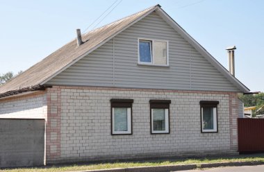 House with calcium silicate (sand lime and flint lime) bricks wall, asbestos roof and metal window shutters. clipart