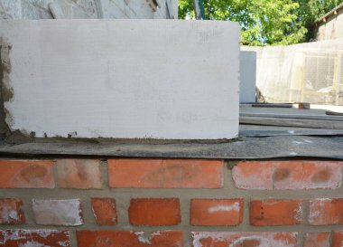 Temelde su geçirmez kaplama. Kırmızı tuğla temel duvarında su geçirmez zarı olan beyaz otoklastır havalandırmalı beton klima blokları.. 