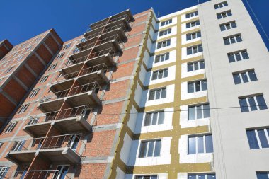 Tuğladan yapılma apartman binasının yanı sıra cam yünü ve strafor yalıtımlı dış termal yalıtım.