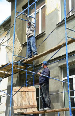 İnşaatçılar onarım, sıva, yenileme, duvarları boyamak için yapı iskelesi kuruyorlar.. 
