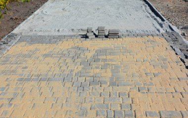 Bahçe yolu oluşturmak için çimento döşeme işlemi. Kiremitleri yerleştirdikten sonra kumla kaplanırlar. Bu da eklemlerdeki boşlukları doldurur..