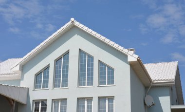Facade of a white house with a white roof and large panoramic windows.